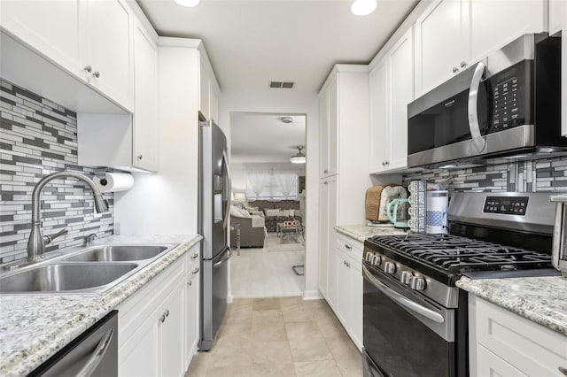 kitchen with white cabinets, decorative backsplash, sink, and appliances with stainless steel finishes