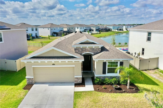 view of front of property with a garage, a water view, and a front lawn