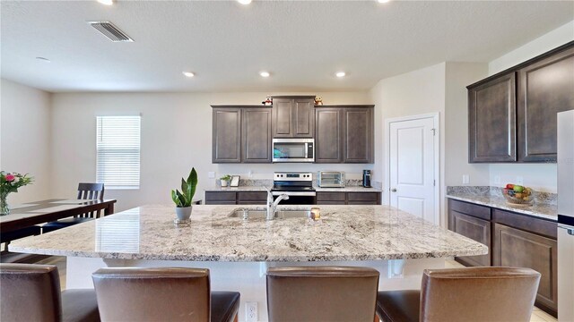 kitchen featuring an island with sink, a breakfast bar area, and stainless steel appliances