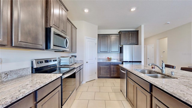 kitchen with light stone counters, appliances with stainless steel finishes, sink, and light tile flooring