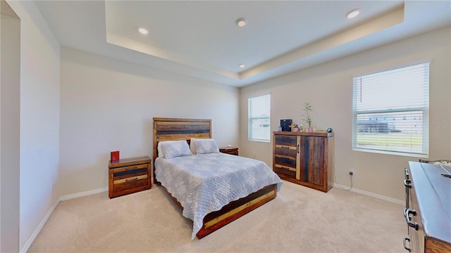 carpeted bedroom featuring a tray ceiling and multiple windows