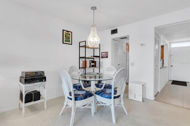 carpeted dining area with an inviting chandelier