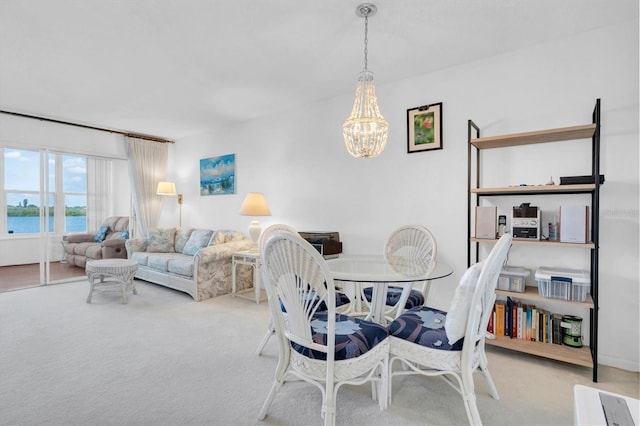 dining space with a notable chandelier, a water view, and light colored carpet