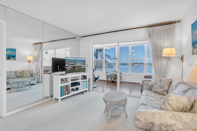 carpeted living room with ceiling fan and a water view