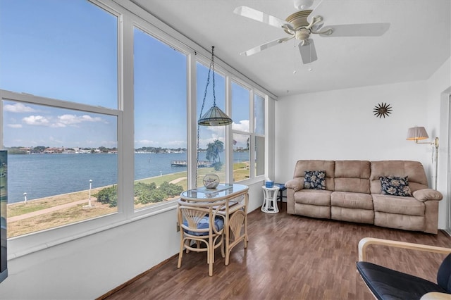 sunroom with ceiling fan and a water view