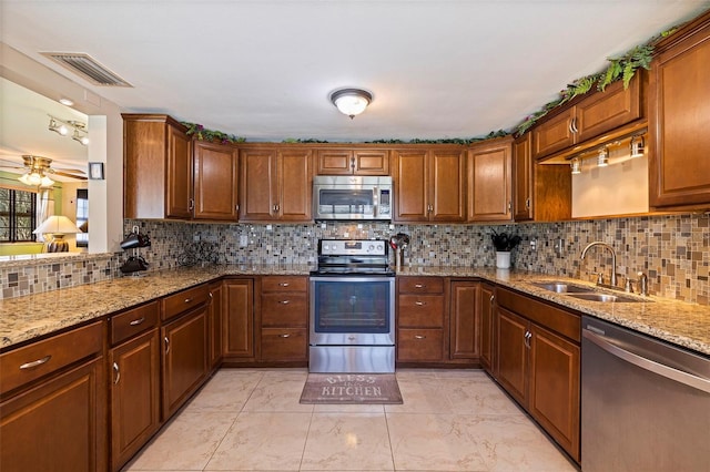 kitchen featuring light tile patterned floors, backsplash, light stone countertops, and stainless steel appliances