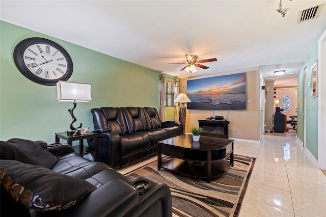 living area with light tile patterned floors, baseboards, visible vents, and a ceiling fan