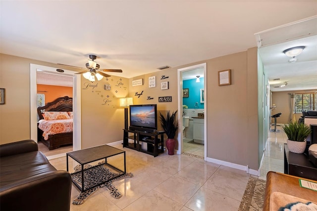 living area with light tile patterned floors, a ceiling fan, visible vents, and baseboards