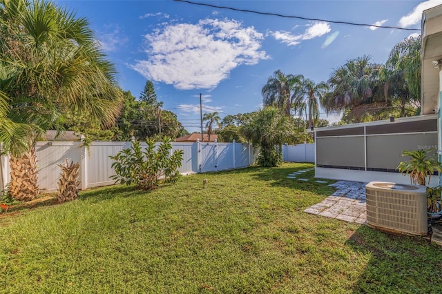 view of yard featuring a sunroom, a fenced backyard, and central AC unit