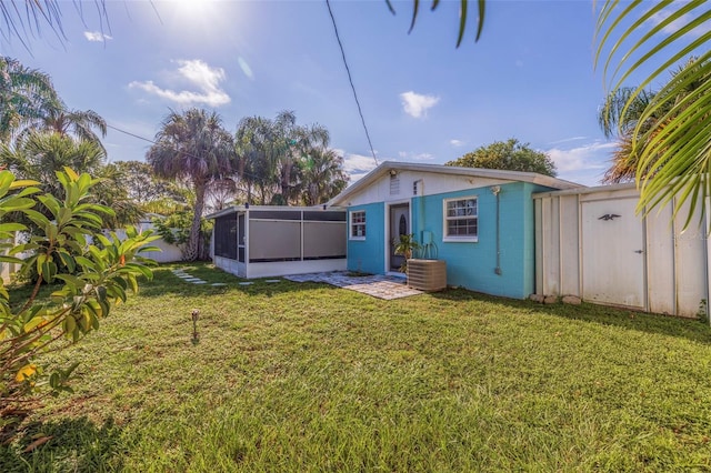 rear view of house featuring fence, concrete block siding, and a lawn