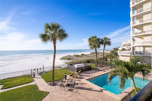 view of swimming pool with a view of the beach, a water view, and a patio