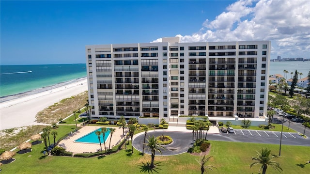 view of property featuring a beach view, a community pool, and a water view