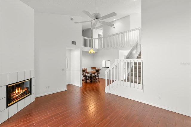 unfurnished living room featuring ceiling fan, a towering ceiling, and a fireplace