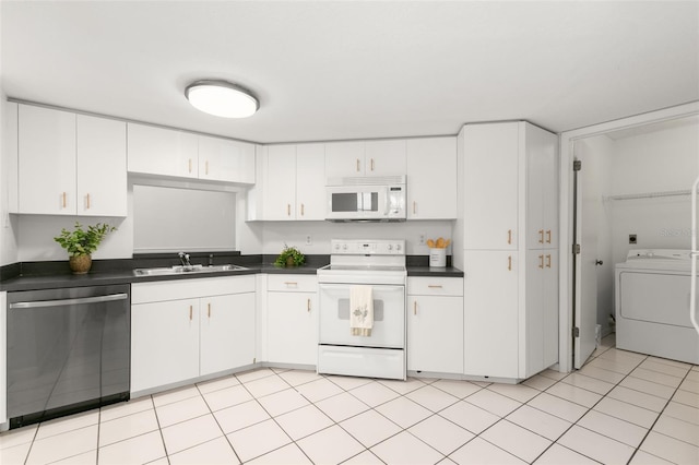 kitchen with washer / clothes dryer, dark countertops, white appliances, and a sink