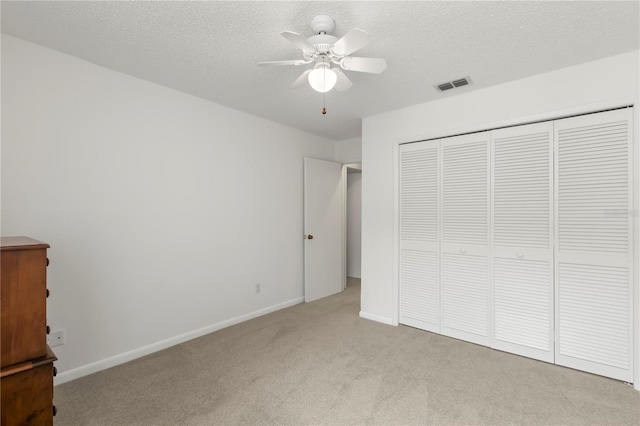 unfurnished bedroom featuring a closet, visible vents, light carpet, a textured ceiling, and baseboards