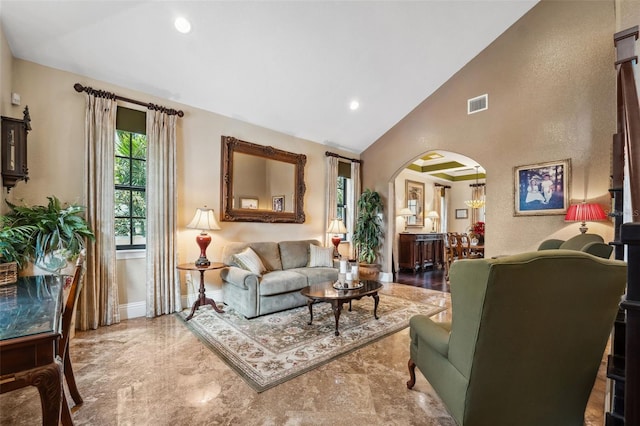 living room with high vaulted ceiling, arched walkways, baseboards, visible vents, and recessed lighting