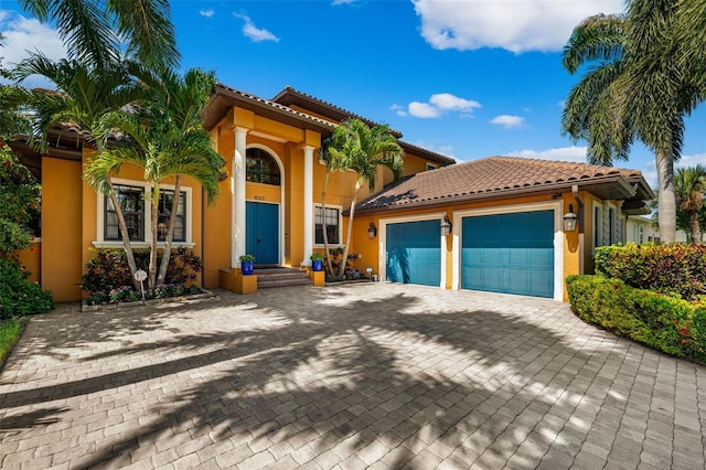 mediterranean / spanish-style house with stucco siding, an attached garage, decorative driveway, and a tile roof