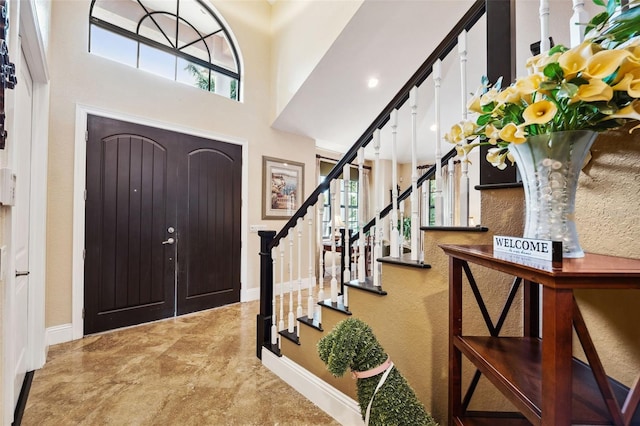 entrance foyer featuring stairs, baseboards, and a high ceiling