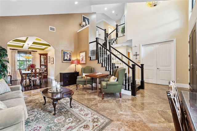 living room with arched walkways, baseboards, visible vents, a high ceiling, and stairway