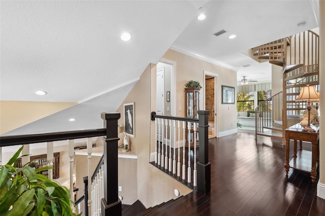 hallway featuring wood finished floors, visible vents, an upstairs landing, and crown molding