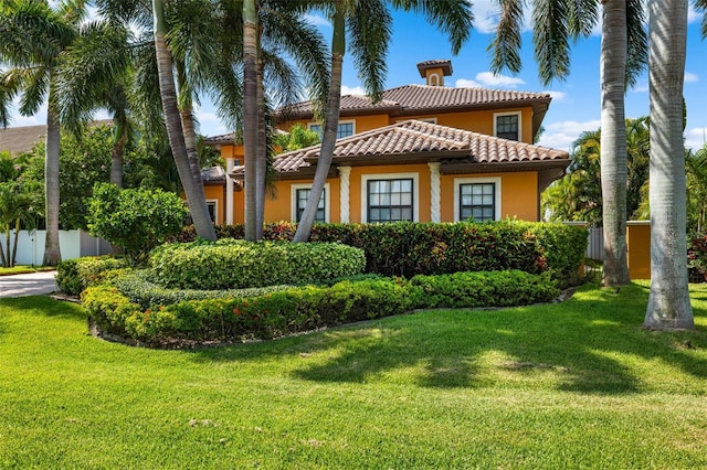 exterior space with a tile roof, a front yard, stucco siding, and fence
