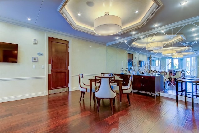 dining room with crown molding, dark hardwood / wood-style floors, and a tray ceiling