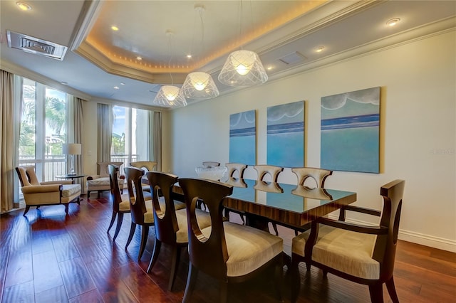 dining area with a raised ceiling, ornamental molding, and dark hardwood / wood-style floors