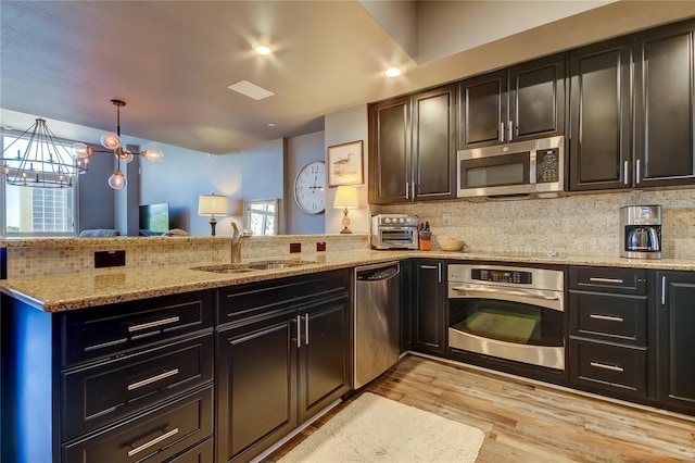 kitchen featuring sink, light hardwood / wood-style flooring, a notable chandelier, stainless steel appliances, and backsplash