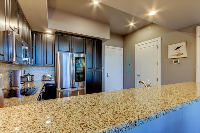 kitchen featuring decorative backsplash, light stone countertops, kitchen peninsula, and appliances with stainless steel finishes