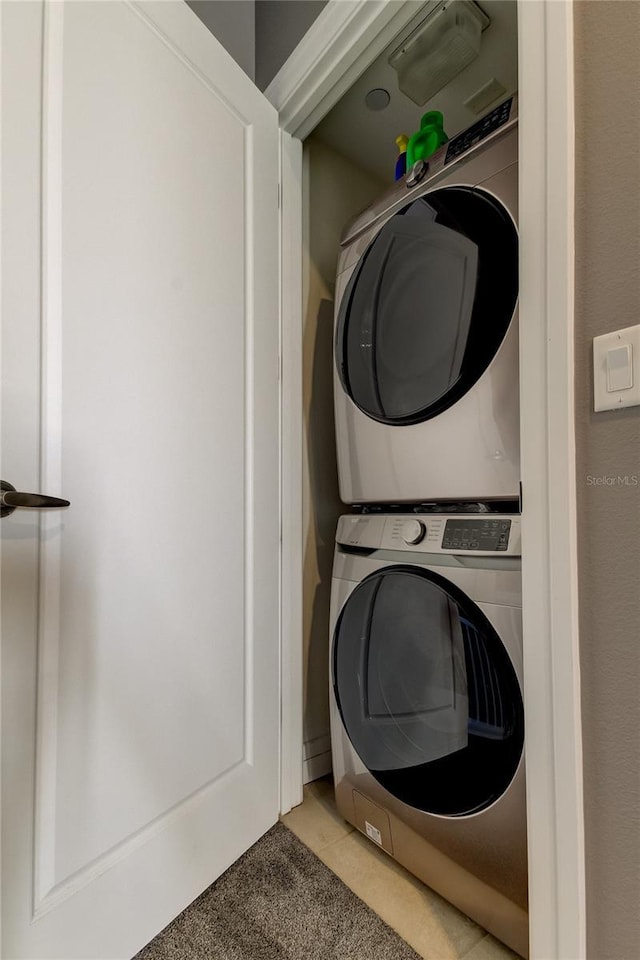 washroom with stacked washer / drying machine and light tile patterned floors