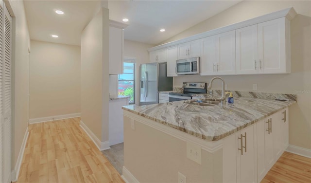 kitchen with kitchen peninsula, stainless steel appliances, light wood-type flooring, white cabinets, and sink