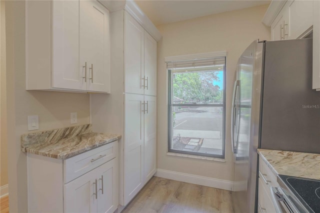 kitchen with light hardwood / wood-style floors, white cabinetry, stainless steel fridge, stove, and light stone counters