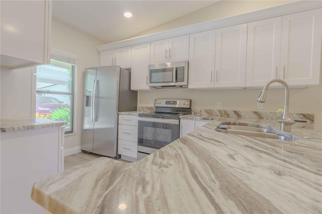 kitchen with stainless steel appliances, sink, light stone countertops, and white cabinets