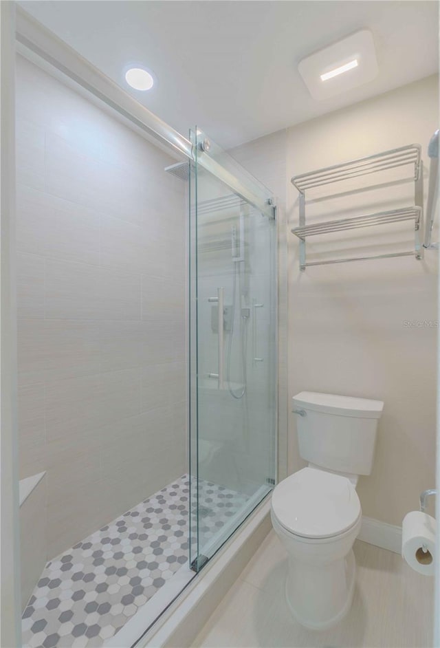 bathroom with tile floors, walk in shower, and toilet