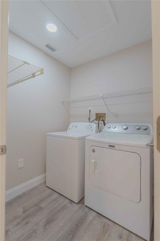 clothes washing area with washer and dryer, light hardwood / wood-style floors, and hookup for a washing machine