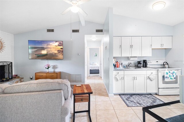 kitchen with vaulted ceiling, sink, light tile patterned floors, electric range, and white cabinetry