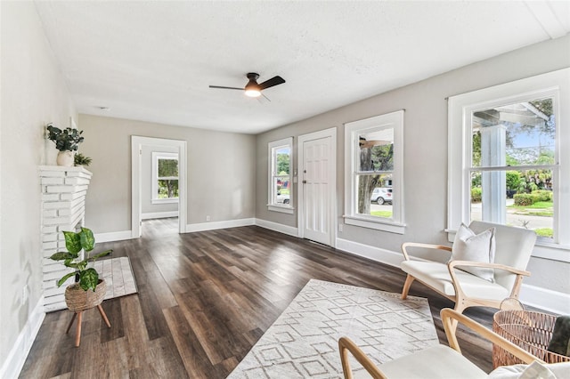 living area with dark wood-type flooring, a textured ceiling, and ceiling fan