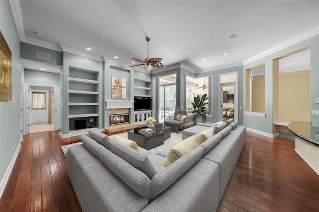 living room with dark hardwood / wood-style flooring, ceiling fan, built in shelves, and crown molding