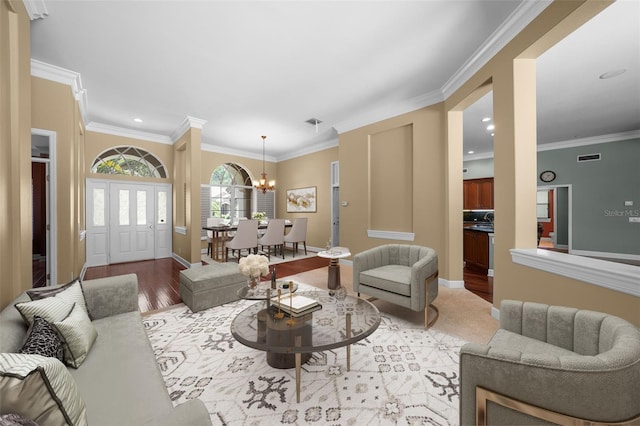 living room with a notable chandelier, light hardwood / wood-style floors, and crown molding