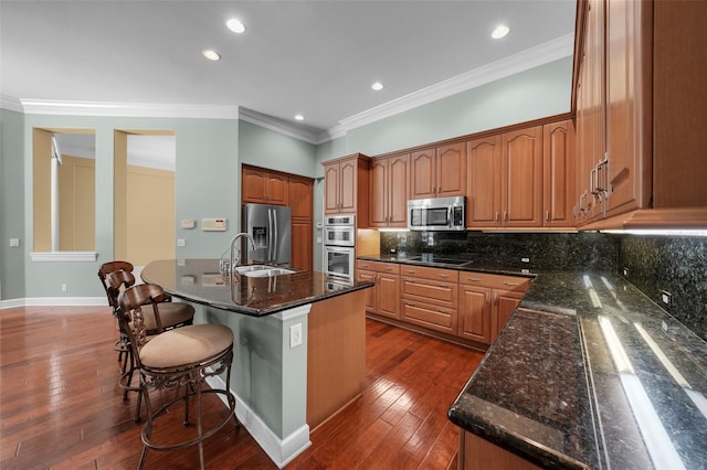 kitchen with ornamental molding, a breakfast bar area, decorative backsplash, dark stone counters, and appliances with stainless steel finishes