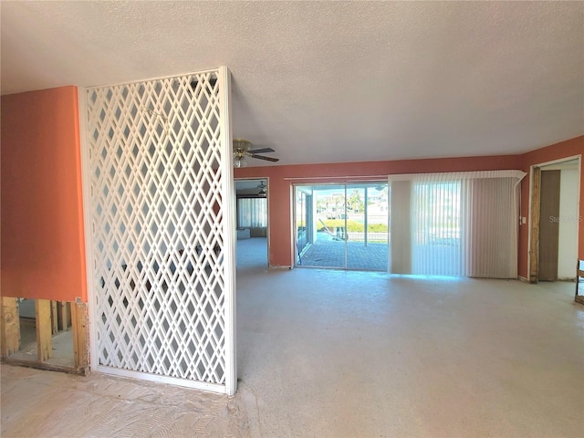 unfurnished living room with ceiling fan and a textured ceiling