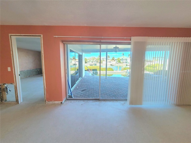 empty room featuring a textured ceiling, a water view, and light carpet