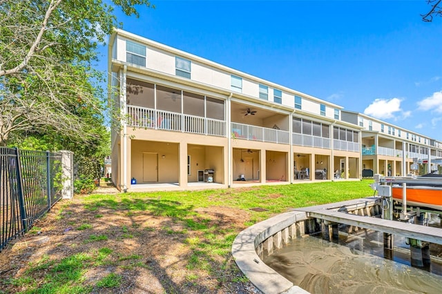 back of property with ceiling fan, a yard, a sunroom, and a patio