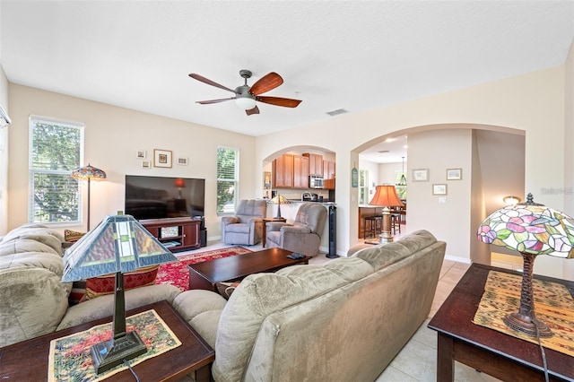 tiled living room with ceiling fan and a wealth of natural light