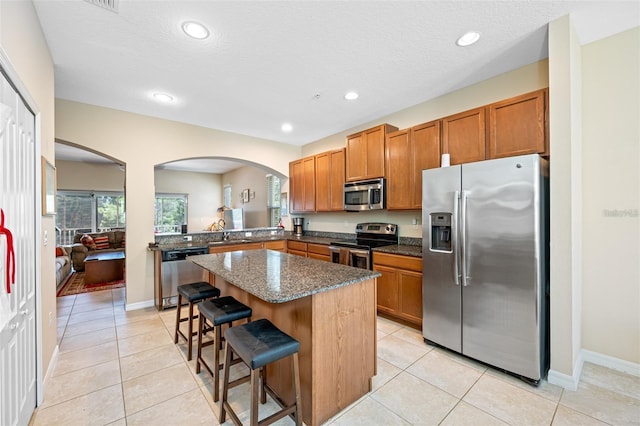 kitchen featuring appliances with stainless steel finishes, a center island, sink, a breakfast bar, and light tile patterned floors