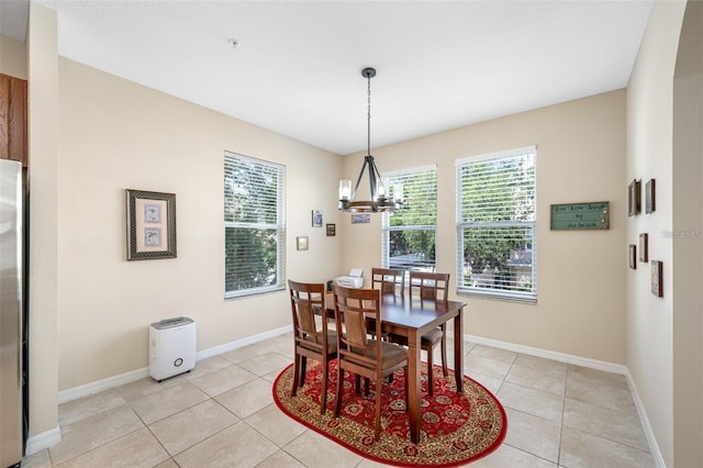 dining area featuring a chandelier, light tile patterned flooring, and baseboards