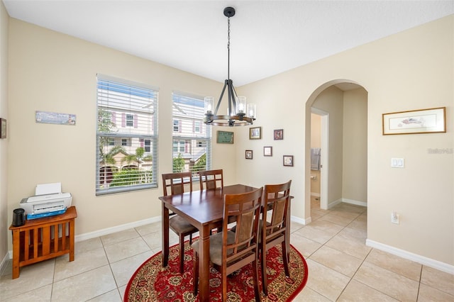 dining space with arched walkways, light tile patterned floors, a chandelier, and baseboards