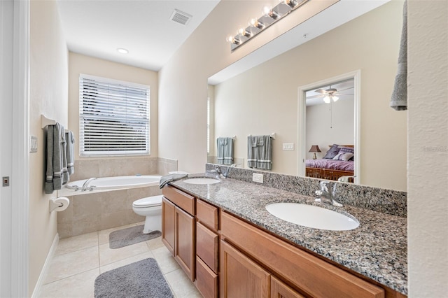 bathroom with tiled tub, tile patterned floors, vanity, toilet, and ceiling fan