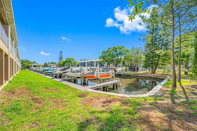 dock area with a water view, boat lift, and a yard