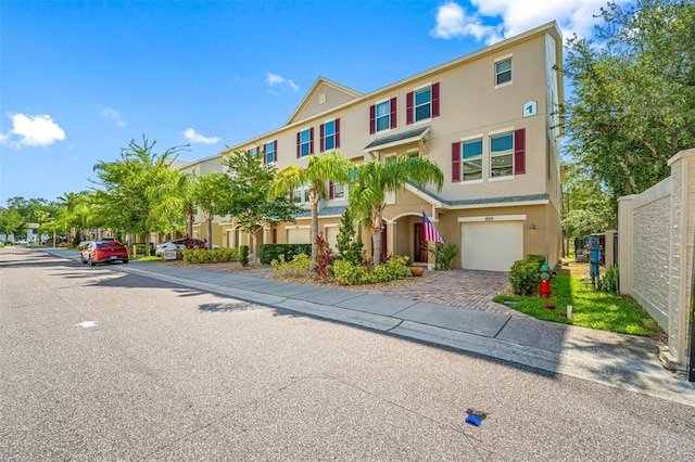 multi unit property featuring driveway, an attached garage, a residential view, and stucco siding